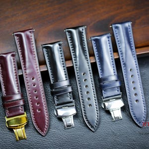 Könnte beinhalten: Fünf verschiedene Uhrenarmbänder in verschiedenen Farben, darunter Schwarz, Marineblau und Burgunderrot. Die Armbänder sind aus Leder und haben eine polierte Metallschließe.