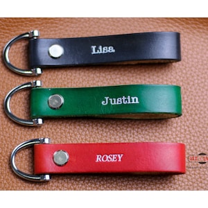 May include: Three leather keychains with silver key rings. The keychains are black, green, and red. The names "Lisa", "Justin", and "Rosey" are embossed in silver on the keychains.
