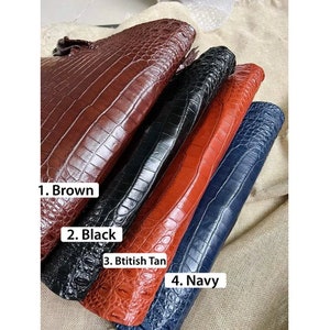 May include: Four rectangular clutches with a textured crocodile skin pattern. The items are labeled as 1. Brown, 2. Black, 3. Btitish Tan, and 4. Navy. Each clutch features a glossy finish and a distinct scale-like surface texture in these four colors.