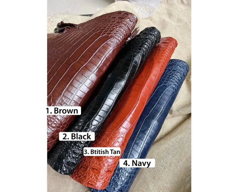 May include: Four rectangular clutches with a textured crocodile skin pattern. The items are labeled as 1. Brown, 2. Black, 3. Btitish Tan, and 4. Navy. Each clutch features a glossy finish and a distinct scale-like surface texture in these four colors.