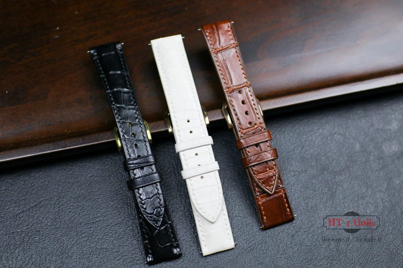 May include: Three different watch straps in black, white, and brown leather. The straps have a crocodile pattern and are made of high-quality leather.