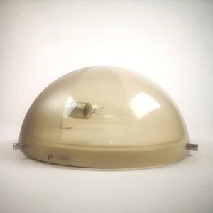 May include: A beige dome-shaped ceiling light fixture with a clear glass shade and a visible light bulb. The fixture has a metal base with the word "g-mobile" printed on it.