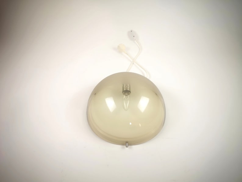May include: A brown glass pendant light fixture with a white cord and a white ceiling mount.