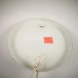 May include: White round ceiling light fixture with a white cord and a small red label that says "Made in Italy".