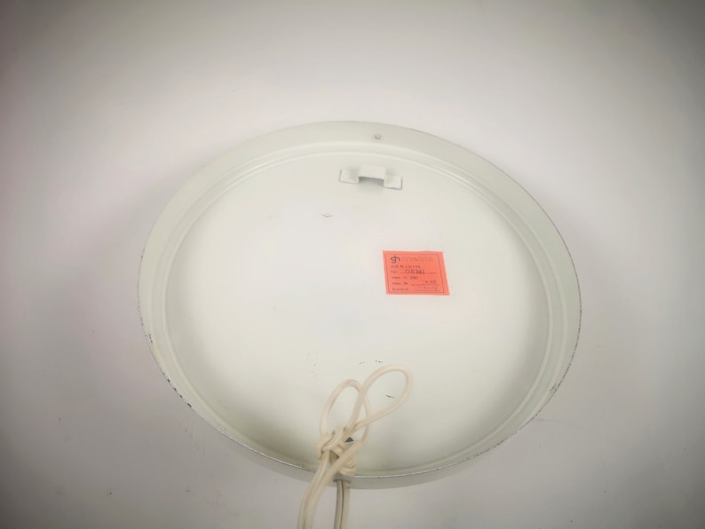 May include: White round ceiling light fixture with a white cord and a small red label that says "Made in Italy".