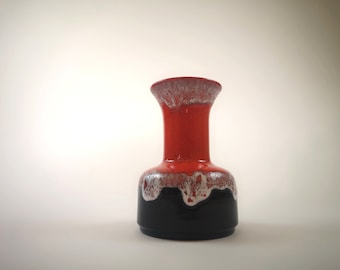 Könnte beinhalten: Eine rote und schwarze Keramikvase mit weißem Überzug. Die Vase hat einen breiten Boden und einen schmalen Hals.