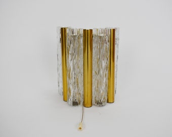 May include: A gold and clear glass wall sconce with a textured glass design. The sconce has a cord with a plug.