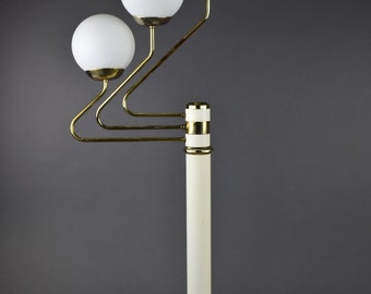 May include: A white and gold floor lamp with three white globe-shaped shades. The lamp has a curved arm and a white base.