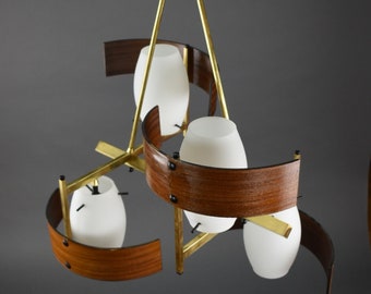 May include: A mid-century modern chandelier with a black and gold finish. The light fixture has three white glass shades, wooden accents, and brass supports. The design is a unique, eye-catching piece.