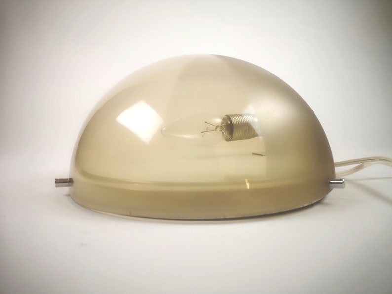May include: A beige frosted glass dome lampshade with a light bulb inside. The lampshade is on a white surface.
