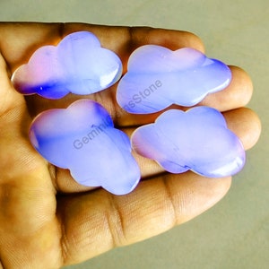 May include: Four purple and white agate cloud shaped cabochons. The cabochons are smooth and polished.