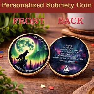 May include: A personalized sobriety coin with a gold rim. The front features a wolf silhouette under a full moon with the text "Find Light in the Darkness." The back has a message of love and gratitude. The coin is on a wooden surface.