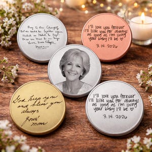 May include: A collection of memorial keepsakes. The keepsakes are round, with a metallic finish in silver, gold, and copper tones. Some feature handwritten messages, while others display a photograph of a woman. The text includes dates and loving sentiments.