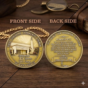 May include: A gold-toned commemorative coin showing both sides. The front features a church building with the text FIRST CHRISTIAN COMMUNITY CHURCH OF ANNAPOLIS, CELEBRATING 35 YEARS 1991-2026. The back displays ROMANS 8:11 and FOUNDED FEBRUARY 22, 1991.