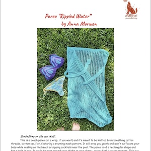 May include: A turquoise crochet pareo, also known as a wrap, is laid out on a bed of green grass. The pareo is made of a breathable cotton yarn and features a delicate mesh pattern. The text "Pareo "Rippled Water" by Anna Morwen" is visible at the top of the image.