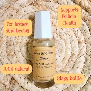 Puede incluir: Botella de vidrio transparente de suero Lash & Brow con tapa blanca. La etiqueta dice "Herbs & Hearth series by Anna Moruien". El texto en la imagen dice "Para pesta&ntilde;as y cejas", "Apoya la salud del fol&iacute;culo" y "100% natural". La botella contiene 10 ml.