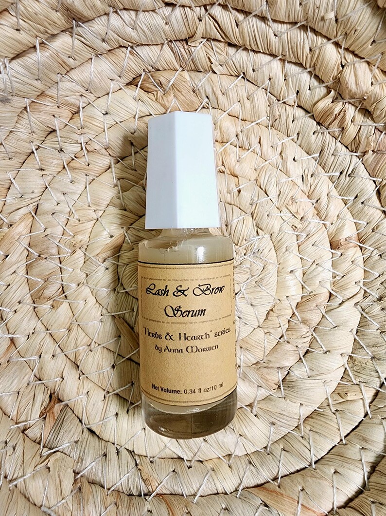 Puede incluir: Una peque&ntilde;a botella de vidrio de suero Lash & Brow con tapa blanca. La etiqueta marr&oacute;n tiene texto negro: "Herbs & Icarth series by Anna Morwen". El volumen neto es de 10 ml.