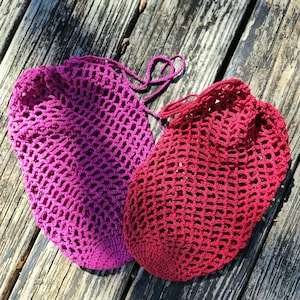 May include: Two crocheted string bags, one pink and one red, with a diamond pattern.