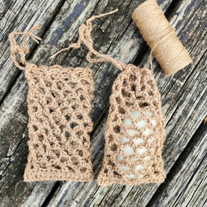 May include: Two brown crocheted bags made of natural fibers, with one bag containing a white bar of soap. A roll of brown twine is also visible in the image.