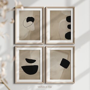 May include: Set of four abstract art prints in a minimalist style. Each print features a different combination of black and beige shapes on a beige background. The prints are framed in light wood frames.