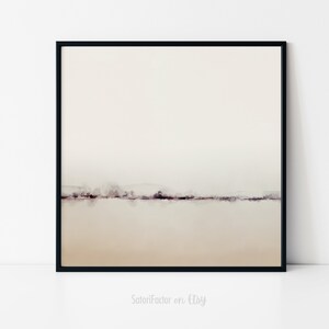 May include: A minimalist watercolor painting of a landscape with a thin line of trees in the distance. The background is a light beige color, and the foreground is a slightly darker beige color. The painting is framed in a black frame.