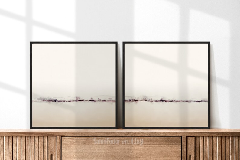 May include: Two framed abstract art prints with a minimalist design. Each print features a horizontal line of muted purple brushstrokes against a light beige background.