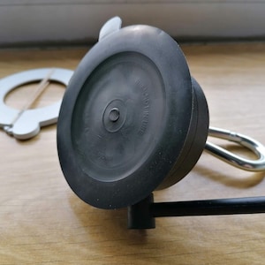May include: A black suction cup with a metal hook and a black handle. The suction cup has the text "NOT IN USE" printed on it.