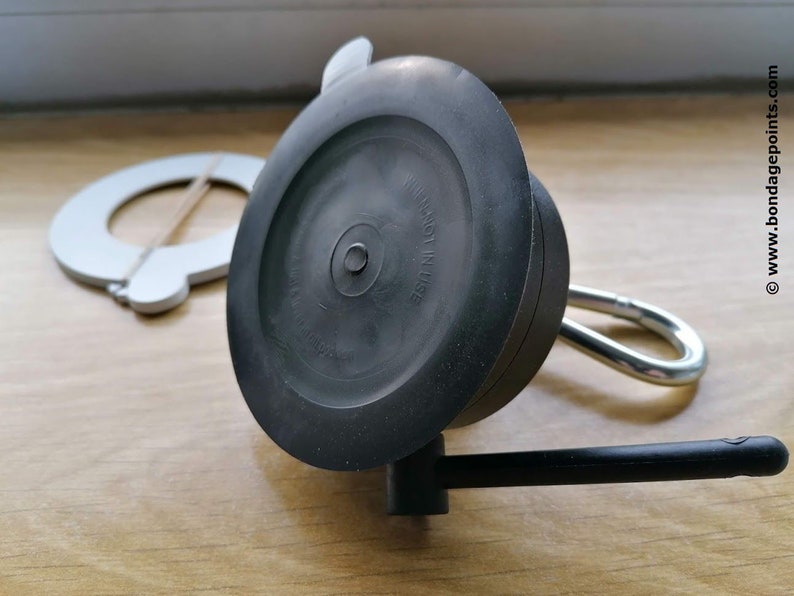 May include: A black suction cup with a metal hook and a black handle. The suction cup has the text "NOT IN USE" printed on it.