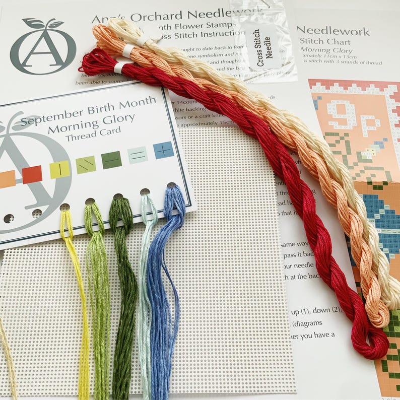 May include: A cross stitch needlework kit featuring a Morning Glory flower design. The kit includes a printed chart, embroidery floss in various colours, a needle, and a piece of Aida cloth.