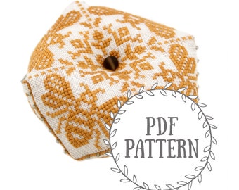 May include: A hexagonal pincushion with a geometric pattern in white and mustard yellow. The pincushion has a hole in the center for pins.