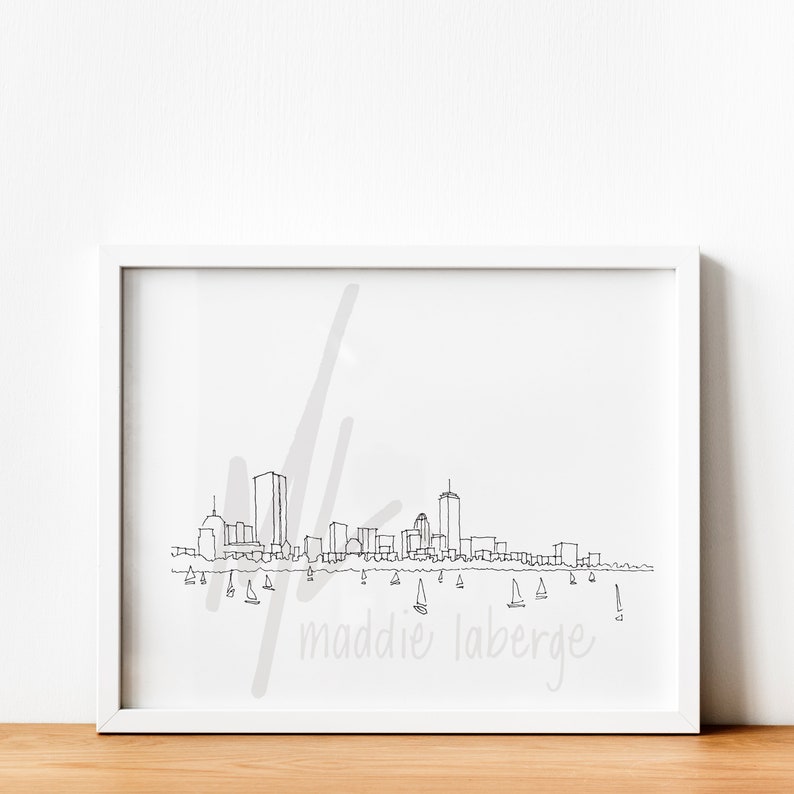 May include: A black and white line drawing of the Boston skyline with sailboats in the water. The name "maddie laberge" is written in cursive at the bottom of the image.