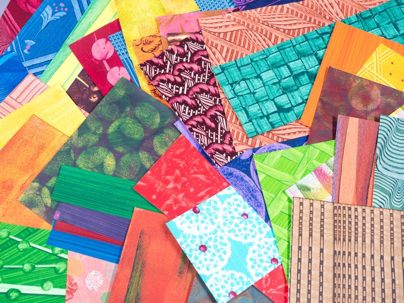 May include: A collection of rectangular paper swatches featuring a diverse array of patterns and colors, including bright yellow, deep green, vibrant orange, red, blue, and brown. The designs include geometric weaves, floral motifs, and textures.