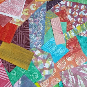 May include: A collage of rectangular and irregularly shaped paper scraps featuring diverse textures and patterns in vibrant colors including red, orange, yellow, green, blue, purple, and pink. The surfaces display embossed, printed, and painted designs.