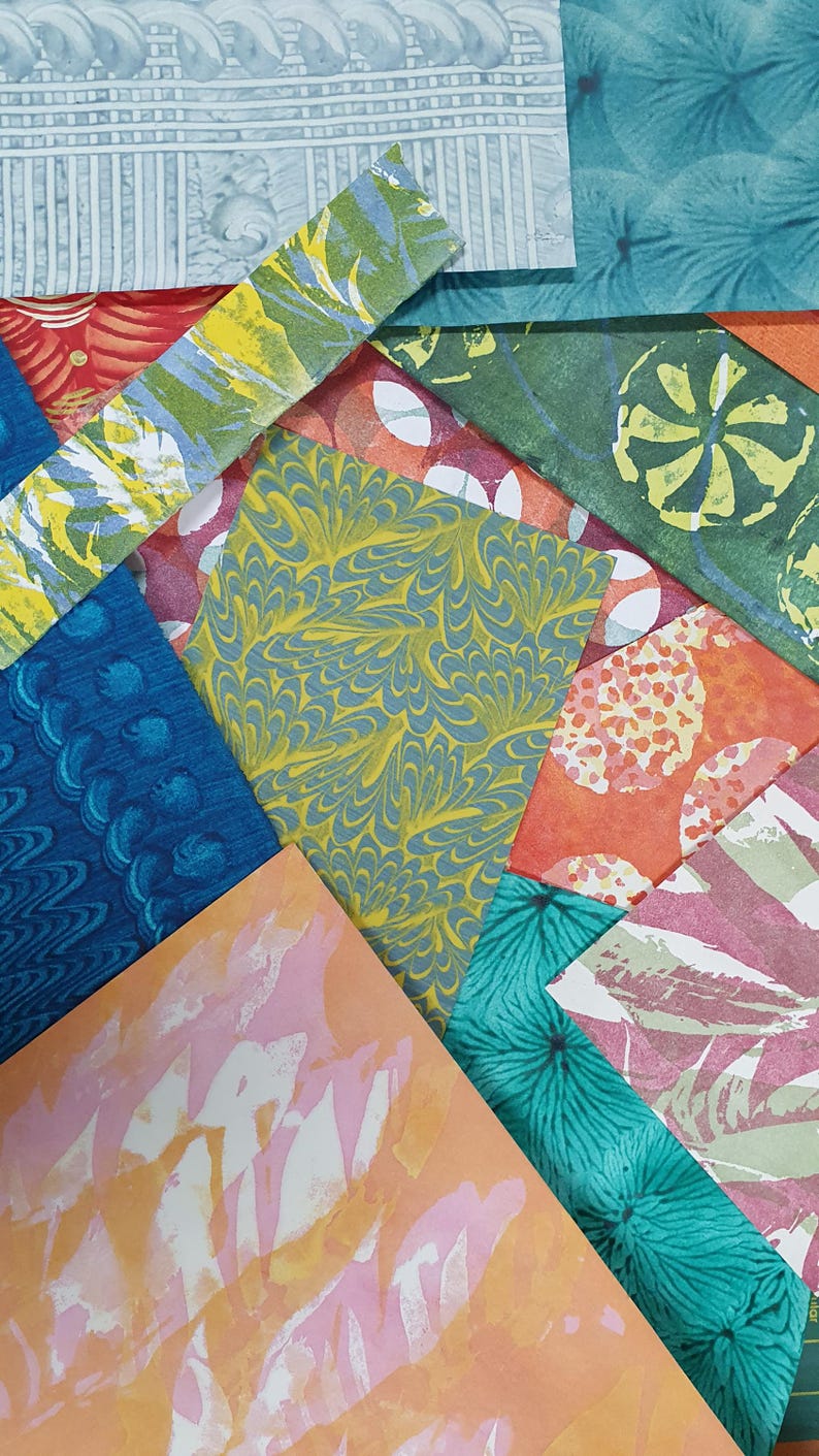 May include: A collection of overlapping rectangular paper sheets featuring diverse patterns and colors, including marbled yellow and blue, teal floral prints, orange circles, pink abstract washes, and architectural gray line designs.