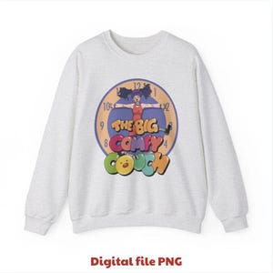 Op de afbeelding: Een lichtgrijs sweatshirt met een kleurrijke afbeelding van de kinderserie "The Big Comfy Couch". De afbeelding bevat een klokontwerp, een stripfiguur en het logo van de show in levendige kleuren.