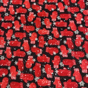 May include: A fabric pattern featuring a repeating design of red mittens and white snowflakes on a black background. The mittens have white striped cuffs and are covered in white speckles, creating a wintery theme.