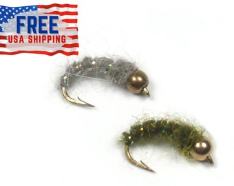May include: Two fly fishing lures, one grey and one green, with gold beads. The lures are tied with a variety of materials, including feathers and thread.