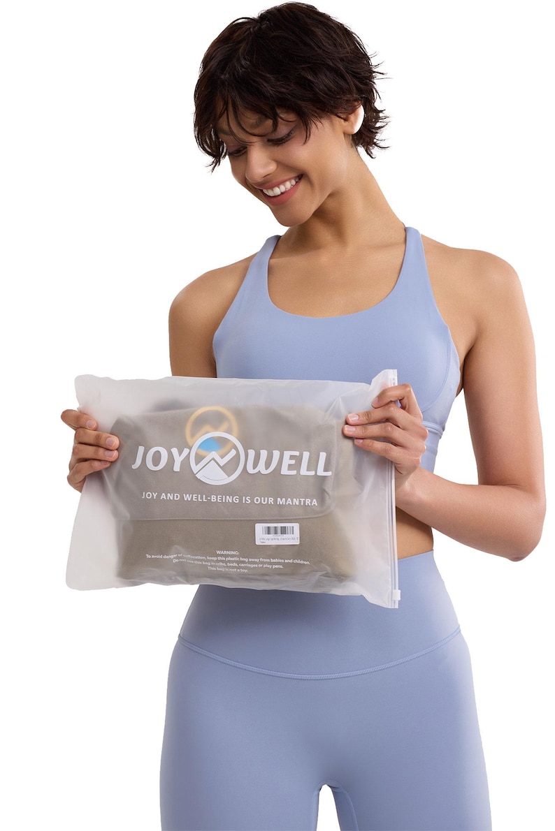 May include: A translucent, frosted plastic storage bag featuring the white text JOY WELL and the phrase JOY AND WELL-BEING IS OUR MANTRA printed on the front. The bag contains a folded olive green textile item and includes a small white barcode label.