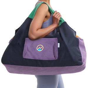 May include: A large, color-blocked tote bag with a purple pocket featuring a mountain logo. The bag has a green strap, a navy blue body, and a purple base. The bag is designed for carrying items.