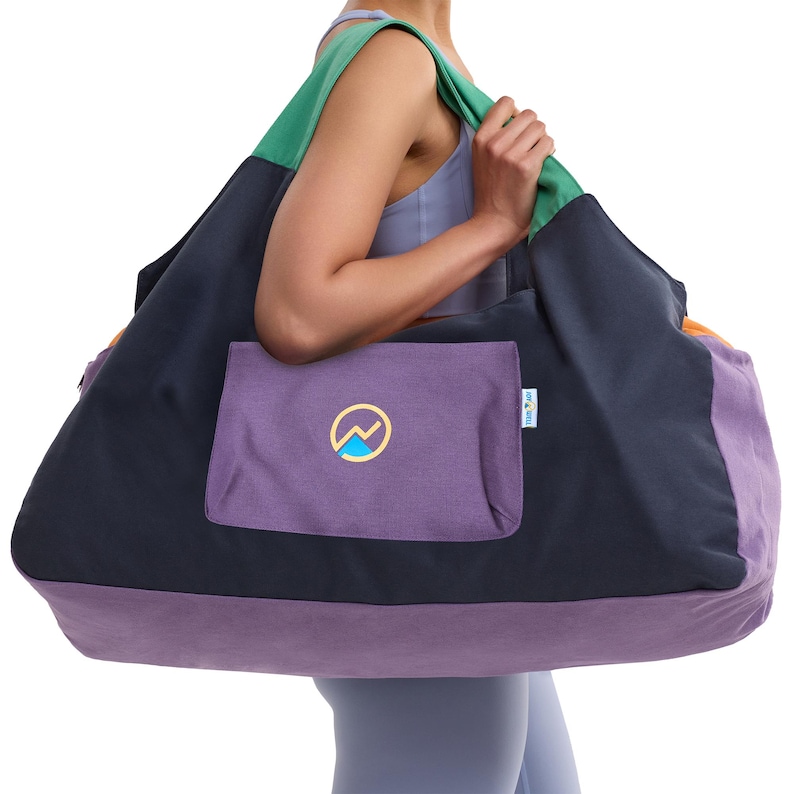 May include: A large, color-blocked tote bag with a purple pocket featuring a mountain logo. The bag has a green strap, a navy blue body, and a purple base. The bag is designed for carrying items.