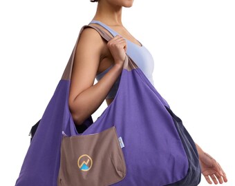 May include: A large hobo-style shoulder bag featuring a vibrant purple main body, a dark navy blue bottom panel, and a taupe-colored shoulder strap. A taupe exterior pocket with a zipper closure displays a circular logo with a mountain graphic.