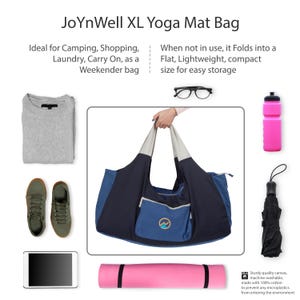 May include: A navy blue and gray XL yoga mat bag with a blue front pocket. The bag is held by a person. The image also shows a gray sweater, green sneakers, a tablet, a pink yoga mat, a pink water bottle, a black umbrella, and glasses. The bag is made of sturdy canvas.