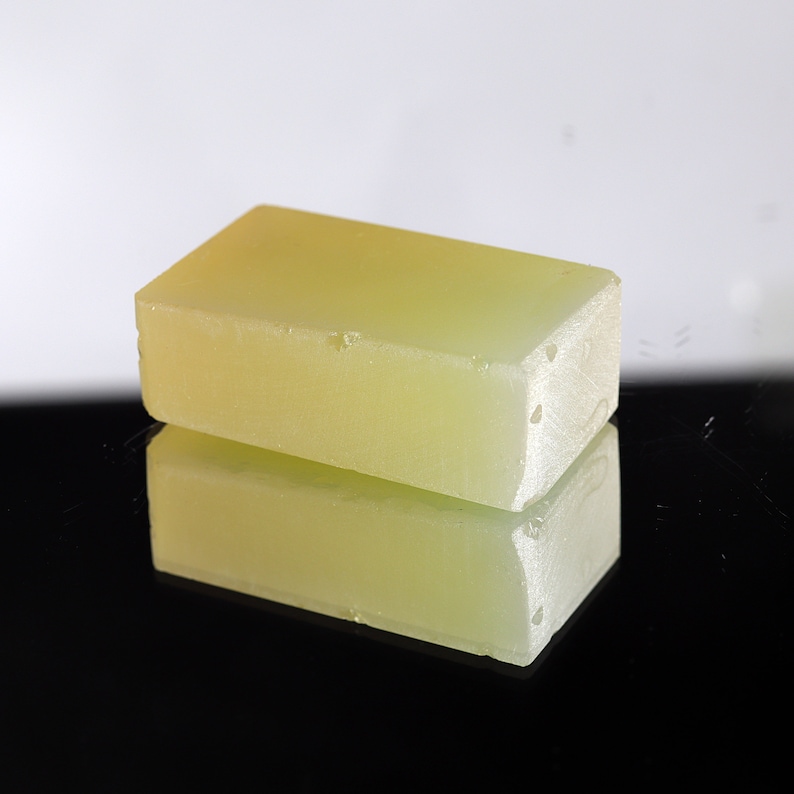Puede incluir: Una barra rectangular de jab&oacute;n amarillo transl&uacute;cido. El jab&oacute;n es liso y tiene un ligero brillo.