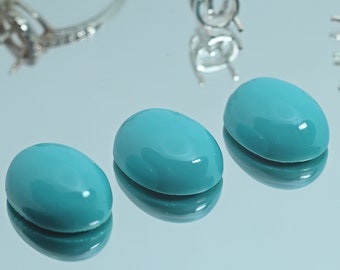 May include: Three oval-shaped turquoise cabochons, each with a smooth, polished surface and a vibrant blue-green colour.