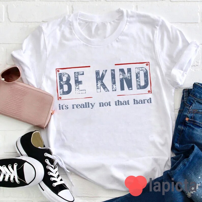 Puede incluir: Camiseta blanca con un gr&aacute;fico azul y rojo que dice "BE KIND it's really not that hard".