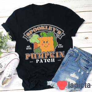 May include: Black t-shirt with a graphic of a pumpkin with a smiling face and the text "Spookley's Pumpkin Patch est. 2001 be kind"