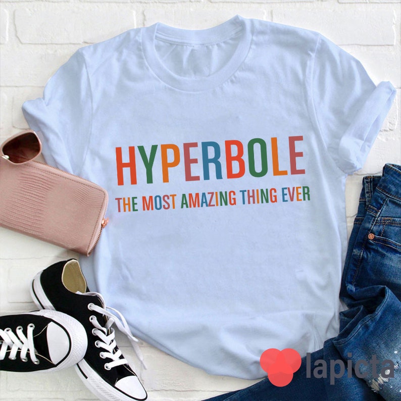 Pu&ograve; includere: Maglietta blu chiaro con il testo "HYPERBOLE THE MOST AMAZING THING EVER" in colori arcobaleno.