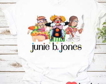 Op de afbeelding: Wit T-shirt met een kleurrijke illustratie van drie meisjes. De meisjes dragen verschillende outfits en hebben verschillende kapsels. De tekst "Junie B. Jones" is onder de illustratie gedrukt.