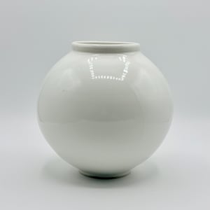 May include: A white, spherical ceramic vase with a wide opening. The vase has a smooth, glossy finish and a rounded shape. The vase is a decorative item, suitable for displaying flowers or as a standalone accent piece.