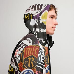 Op de afbeelding: Een zwarte capuchontrui met een kleurrijk, multi-patroon ontwerp. De trui heeft verschillende grafische ontwerpen en tekst, waaronder "Krock", "Fluffhead" en "Mind. Blow. Ride."